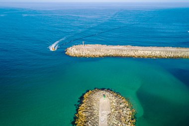 Bir kıyı gemisi bir limanın dalgakıranına giriyor. Drone görünümü