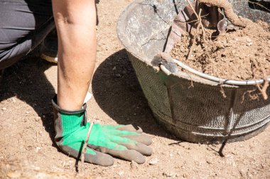 Arkeolojik bir kazı üzerinde çalışırken kazanın yanında bir arkeologun eli..