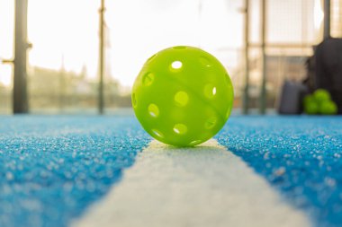 Pickleball sahasında bir top, raket spor konsepti arka planda