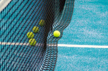 Mavi bir Padel tenis kortunda beş top, raket spor arka planı.