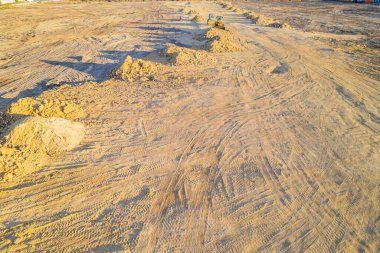 İnşaattaki arazi, makinelerle toprağı hareket ettiriyor ve bir inşaat alanı tarafından kazılmış büyük bir toprak yığını.