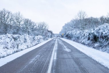 Kış kar yağışı sırasında buzlu bir arazide yol manzarası, kış konseptinde ulaşım