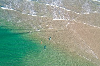 Sörfçüler plajda turkuaz suyla sörf yapıyorlar, drone ile havadan gözetleme yapıyorlar. Yaz konsepti için arkaplan