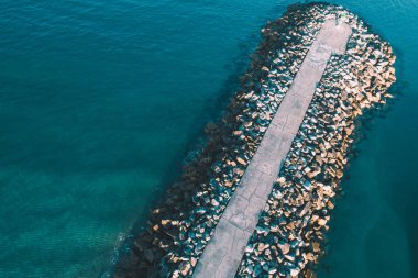 Gün batımında bir limandaki büyük granit blokların dalgalanması insansız hava aracından, hava fotoğrafından görüldüğü gibi.