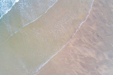 Güneş doğarken turkuaz suyu olan bir kumsalın kıyısı, yaz ve sahil konsepti, insansız hava aracı ile gökyüzü manzarası.