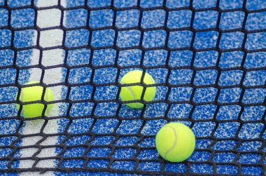 Raket sporu konsepti için arka planda, raket tenis kortunun arkasında üç raket tenis topu.