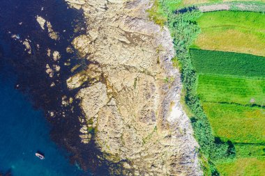 Kayalık bir kıyı şeridinin kayalık kıyısı ve tarım alanları, insansız hava aracı ile hava manzarası, kıyı konsepti için arka plan