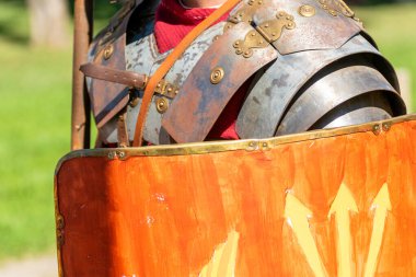 view of the metallic armour and shield of a roman legionary at a historical reenactment festival clipart