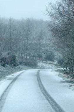 Karla kaplı bir yolda tekerlek izleri, kışın bir dağ yolunda kar altında lastik izleri.