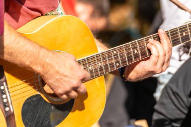 Fretboard 'da gitaristin elini yakın plan çekiyoruz. Açık havada gitar çalan bir adam.