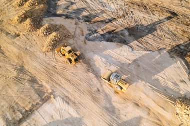 İnsansız hava aracı görüntüsü. Bir inşaat projesi sırasında ağır makineler çalışıyor, toprağı hareket ettiriyor ve inşaat alanındaki manzarayı şekillendiriyor.