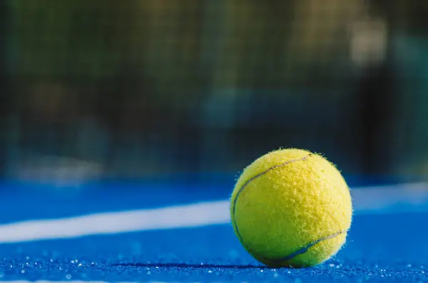 Mavi raket tenis kortunda yalnız bir raket tenis topu, düz yüzey görüşü. Kürek tenis konsepti için arka plan.