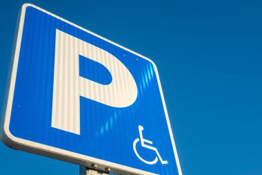 Mavi arka planı olan özel gereksinimleri olan sürücüler için park yeri tabelası, engelli park yeri sembolü tekerlekli sandalye.