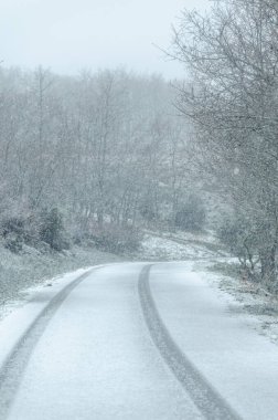 Kar yağarken yol manzarası, karda lastik izleri.