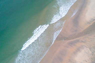 Köpük dalgaları ve canlı turkuaz su ile kumsalın genel manzarası, hava aracının sükunet görüşü kavramı