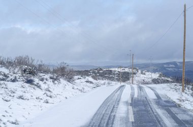 Terk edilmiş karla kaplı dağ yolunda araç lastik izleri, kış taşımacılığı konsepti