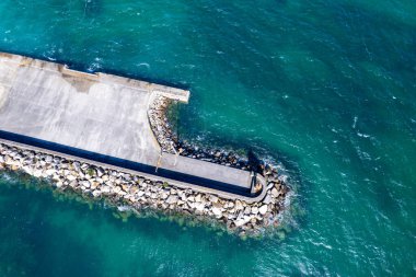 Açık turkuaz su denizindeki bir dalgakıranın hava görüntüsü, İHA 'nın yukarıdan görünüşü