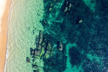 Arka plan olarak kayalık kıyı. Yazın güzel doğal egzotik turkuaz deniz suyu. Hava aracı üst görünümü