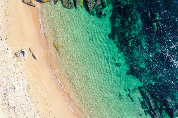 Kumlu kumsalın kayalık okyanus tabanıyla birleşiminin insansız hava aracı görüntüsü. Havadan insansız hava aracı aşağı bakıyor. Arkaplan plaj konsepti dokusu
