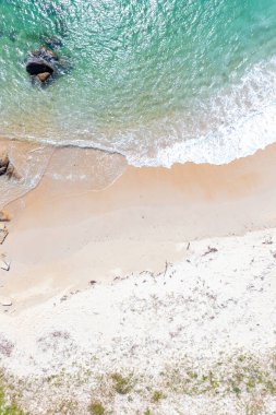 Sakin okyanus dalgaları kumlu kıyılarla buluşuyor, detaylı kıyı dokusu kum ve deniz köpüğü hava aracı görüntüsü