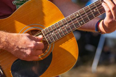 Çelik telli akustik gitarda akor oluşturan parmaklar, akustik gitar çalan ellerin yakın çekimi.
