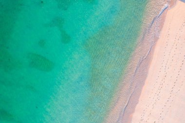 Yukarıdan pembe kumlu bir sahilde deniz mavisi dalgaları. Arkaplan dokusu kavramı yazı