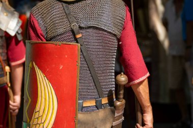 Antik Roma askeri üniforması ve tabancası, Roma zırhı ve kalkanları arkadan.
