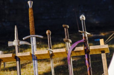 Ortaçağ savaş silahlarının yeniden canlandırılmasında tahta bir stantta dikey olarak sergilenen antik kılıçlar.