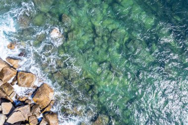 Arka plan olarak kayalık sahildeki dalgalar. Yaz mevsiminde çok güzel doğal bir arka plan. Yukarıdan aşağıya hava aracı görünümü