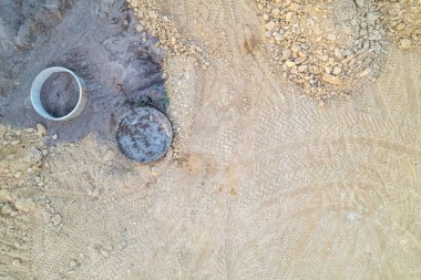 İnşaat alanı detaylarının yukarıdan aşağıya havadan görüntüsü, rögar kapaklı ve beton halkalı bir inşaat alanının insansız hava aracı görüntüsü.