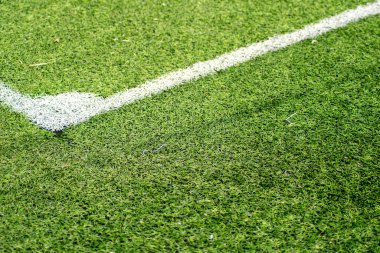 Futbol sahasının köşesine yakın çekim, yeşil sentetik futbol sahasındaki beyaz çizgilerin ayrıntıları.