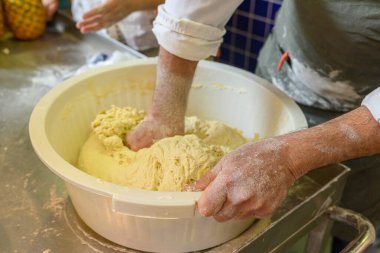 Ekmek hamuru hazırlamak için su, tuz ve un yoğuran bir adamın eli.