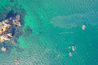 Zenital hava aracı kıyıya yakın turkuaz sularda balıkçılık yapan balıkçı teknelerini görüyor. Geleneksel Deniz Balıkçılığı Konsepti