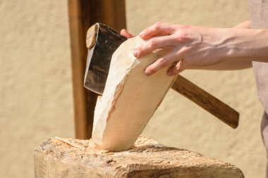 Bir zanaatkar küçük bir baltayla bir tahta parçası üzerinde çalışır.