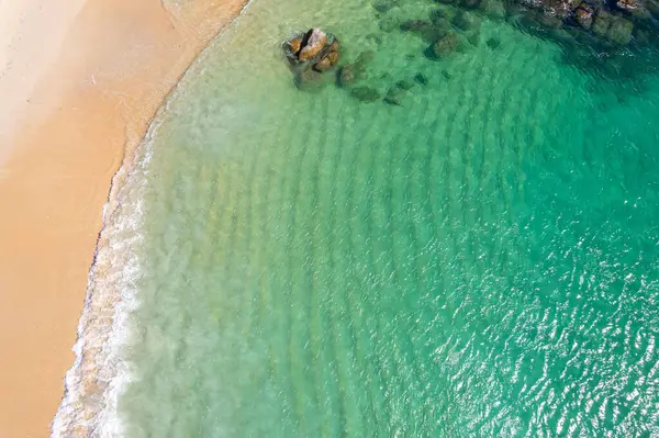 Turkuaz deniz yüzeyi ve hafif kum, hava sahili fotoğrafçılığı.