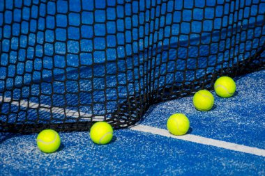 Seçici odaklanma. Mavi raket tenis kortunun ağı ve beyaz çizginin yanında sekiz top. Seçici odak.