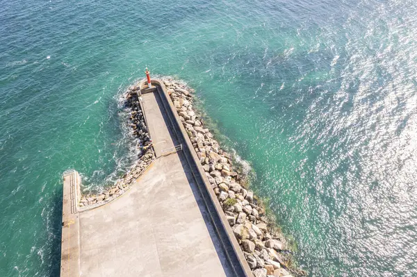 Temiz okyanus dalgalarıyla çevrili uzun ve beton bir dalganın soyut perspektifi, insansız hava aracının görüntüsü.