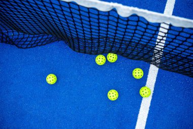 Yüzeyin üstünde, mavi bir sahada, ağın yanında altı tane yankesicilik topu.