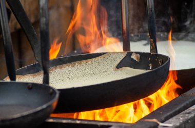 Bir sokak pazarında büyük bir ateşin üstünde krep pişiriyorum.