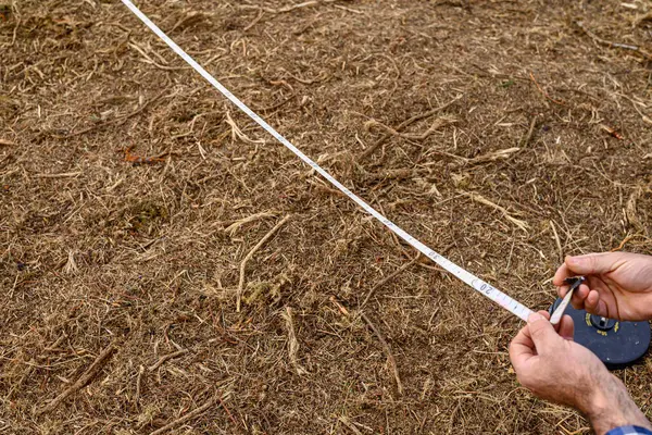 Bir Arazi Çizelgesini Ölçmek için Ölçüm Bantını Kullanan Araştırmacı