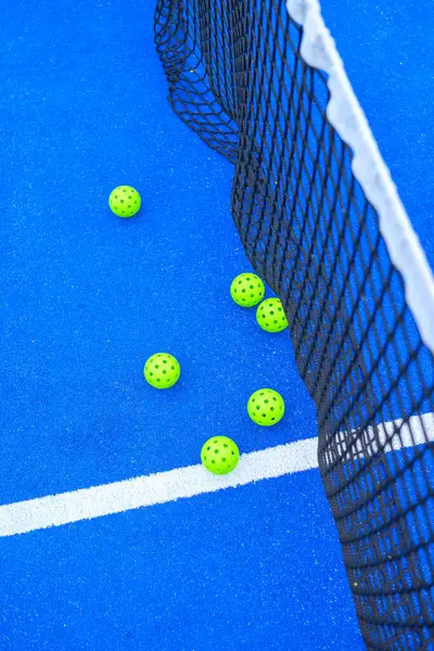 Mavi padel tenis kortunun yukarıdan görünüşü, ağlı ve sarı toplu.