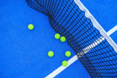 Boş bir Pickleball sahası ve Net tarafından dağıtılmış toplar. Eğlenceli ve enerjik bir oyunun sonucunu kabul et.