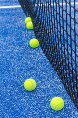 Padel topları antrenman için ağın yanına dizildi..