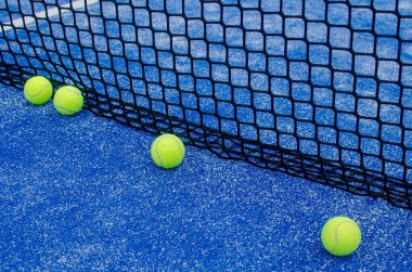 Mavi suni çimen kortunda bir sıra tenis topu..