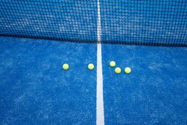 Mavi suni çimen kortunun beyaz çizgisi üzerinde Padel tenis topları.