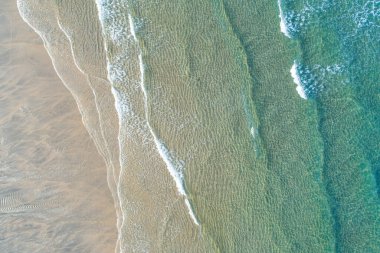 Temiz, turkuaz suyu olan el değmemiş bir kıyı şeridinin soyut arkaplanı.