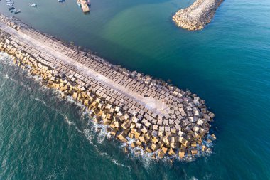 Büyük bir okyanus dalgalanması ve limanın havadan görünüşü, bir kıyı koruma yapısı..