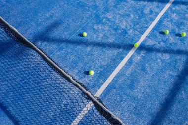 Antrenman seansı konseptinden sonra topları dağılmış mavi bir padel kortun yukarıdan aşağı hava görüntüsü.