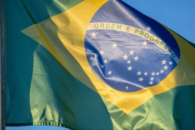 Mavi gökyüzü ulusal gurur kavramına karşı rüzgarda dalgalanan Brezilya bayrağı.