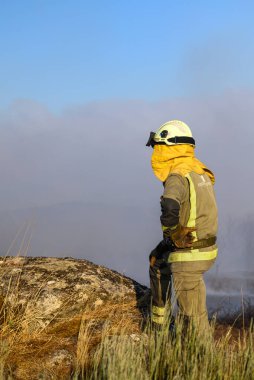 Yalnız bir itfaiyeci Dumanlı bir arka plana karşı bir tepede duruyor